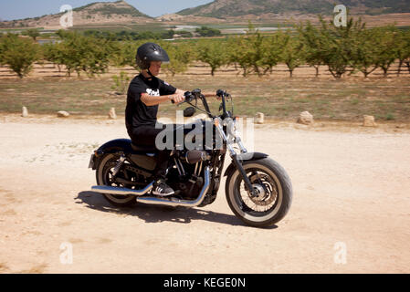 Giovane uomo vestito di nero su un motociclo nero Foto Stock