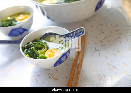 Grande ciotola con piccole ciotole di zuppa di spinaci e uova in camicia Foto Stock