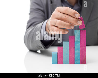 Imprenditore la costruzione di una rampa di scale con il giocattolo dei blocchetti di legno, il successo aziendale e il concetto di sviluppo Foto Stock