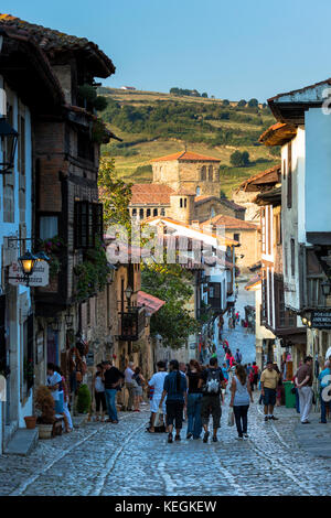 I turisti a piedi passato edifici medievali lungo la strada di ciottoli di Calle del cantone in Santillana del Mar Cantabria, Spagna settentrionale Foto Stock