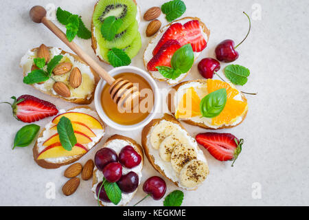 Selezione di estate naturale colorata spuntini salutari. Panini con miele, frutta, bacche Foto Stock