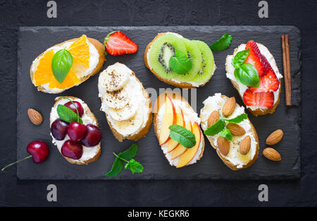 Estate assortiti snack dolci. La bruschetta o panini con frutti e bacche. Vista superiore Foto Stock