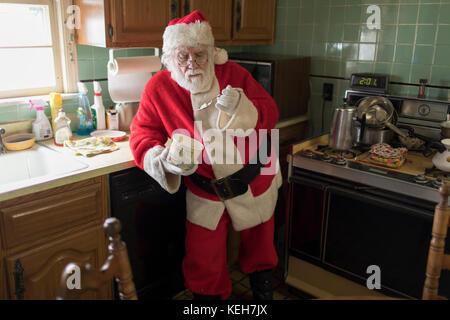 Caucasian Santa a mangiare il gelato in cucina Foto Stock
