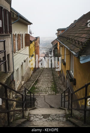 Antico borgo medievale di pietra strette strade lastricate di Buda del distretto di budapest in un giorno di nebbia in inverno. shot a Gul Baba utca Foto Stock