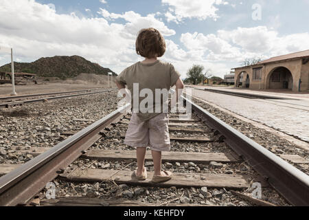 Ragazzo caucasico in piedi con le mani sui fianchi sulla pista del treno Foto Stock