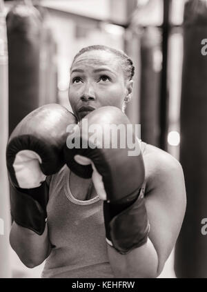 Ritratto di donna nera che indossa guanti di boxe guardando in alto Foto Stock
