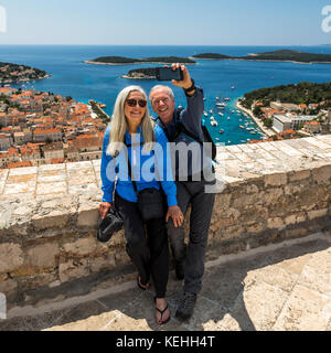 Coppia caucasica in posa per selfie di telefono cellulare con vista panoramica dell'oceano Foto Stock