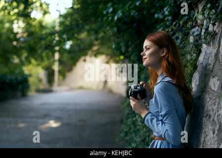 Donna caucasica che fotografa con la macchina fotografica vicino muro di pietra Foto Stock