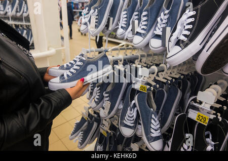 Le mani della donna caucasica holding sneakers in negozio Foto Stock