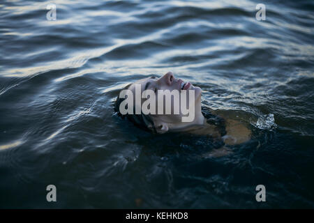 Donna caucasica che galleggia in oceano con gli occhi chiusi Foto Stock