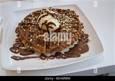 Grandi chiacchiere con gelato alla vaniglia, fuso nutella e noci tritate, Worthing, Regno Unito Foto Stock