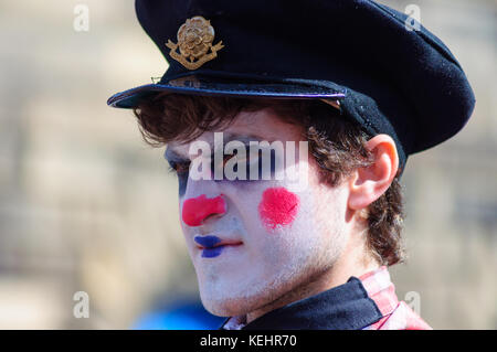 Esecutore maschio con la faccia dipinta e indossando un cappello sulla strada alta durante la frangia di Edinburgh Foto Stock