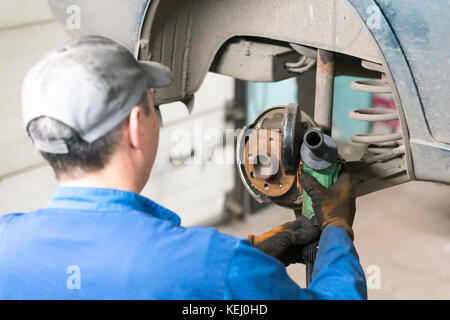 Autofficine mani sostituire i freni in garage. meccanico operaio tecnico installazione auto ruota a manutenzione. lavoratore cambiare disco freno disco freno in Foto Stock