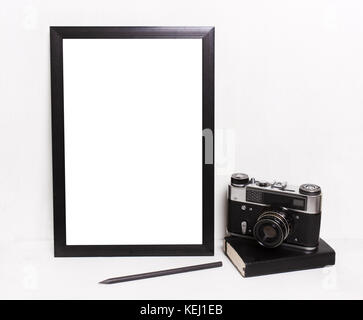 Nero bianco cornici su sfondo bianco ,fotocamera vintage, notebook. mockup in stile hipster workspace Foto Stock