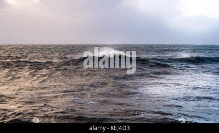 Luce del sole che si infrangono attraverso le nuvole pesanti. Spettacolare vista costiera al mattino presto, quando Atlantic Storm Brian raggiunge la Cornovaglia meridionale, Regno Unito Foto Stock