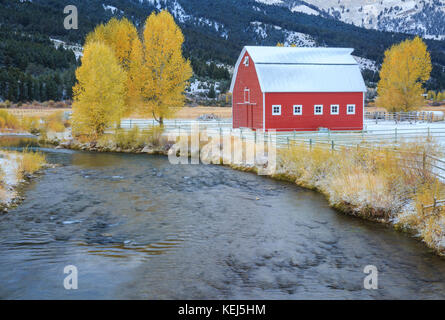 Granaio rosso e i colori dell'autunno lungo il fiume rubino vicino ontano, montana Foto Stock