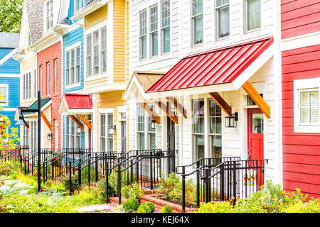 Riga di colorati, rosso, giallo, blu, bianco, verniciato di verde case residenziali, case, case in mattoni con patio giardino in estate Foto Stock