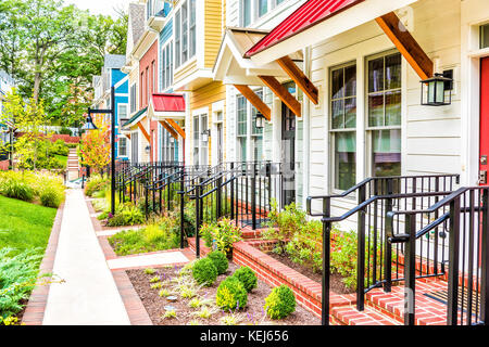 Riga di colorati, rosso, giallo, blu, bianco, verniciato di verde case residenziali, case, case in mattoni con patio giardino in estate Foto Stock