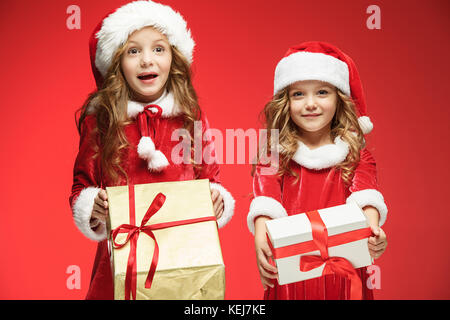 Due ragazze felici in santa claus cappelli con confezioni regalo presso lo studio Foto Stock