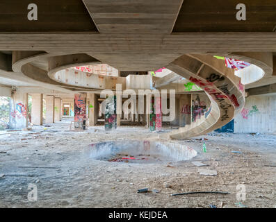 Una scala a chiocciola in cemento in un edificio incompiuto e abbandonato Foto Stock