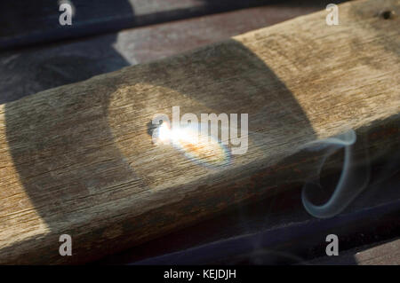 Lente di ingrandimento utilizzata per bruciare il legno Foto Stock