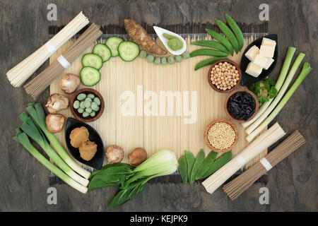 Macrobiotica la dieta alimentare con wasabi in pasta e dadi, udon e sobu tagliatelle, tofu, miso, legumi, alghe wakame, grani e le verdure sul bambù. Foto Stock