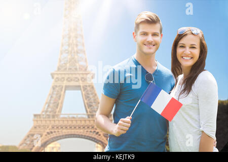 Coppia felice azienda bandiera francese di fronte alla torre eiffel Foto Stock
