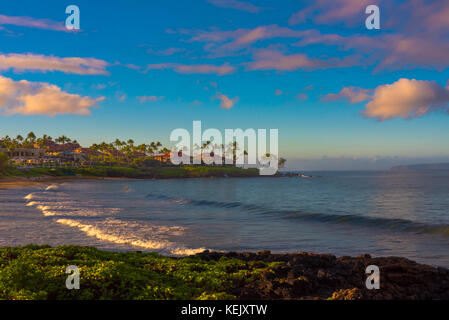 Il Golden Sun del tardo pomeriggio illumina una spiaggia a maui hawaii come onde arrotolate delicatamente a terra. Foto Stock