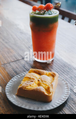 Pesche torta in chiffon sulla piastra bianca e fredda anguria miscelato con ghiaccio e tè verde smoothie drink sul tavolo di legno al ristorante. selet Foto Stock