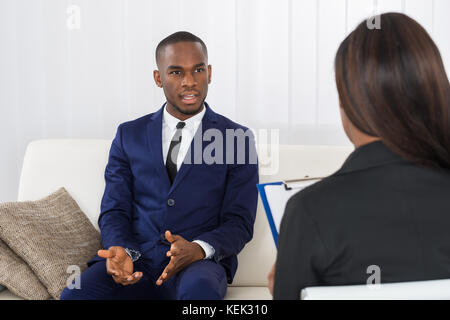Giovane americano africano uomo per spiegare i suoi problemi per lo psicologo Foto Stock