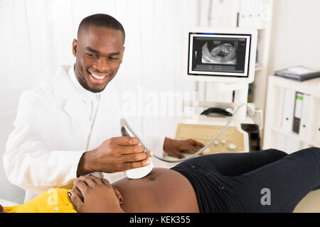 Ginecologo controllo della donna incinta, ventre con trasduttore a ultrasuoni in ospedale Foto Stock