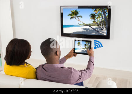 Felice coppia seduti sul divano a guardare la televisione Foto Stock