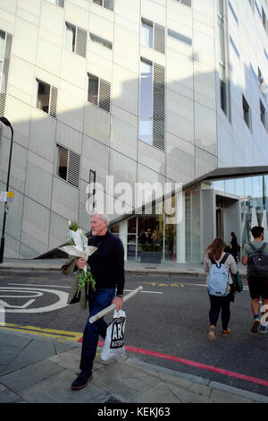 Uomo caucasico trasportare bouquet di fiori e di arte alimenta mentre la strada di attraversamento al di fuori M da Montcalm Hotel, Tech City, Shoreditch, Londra, Inghilterra Foto Stock