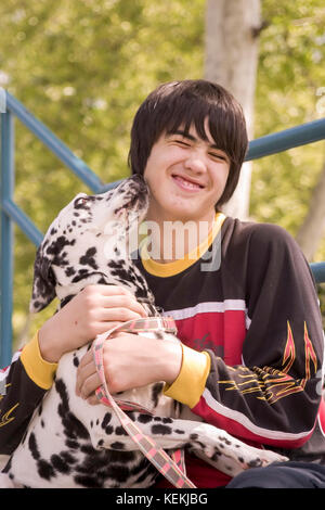 Bambino abbraccia cane giovane adolescente holding e giocare con il cane mostra affetto al proprietario del cane baci kiss leccare la faccia vista frontale © Myrleen Pearson Foto Stock