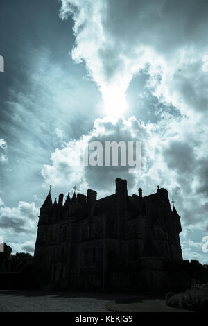 Blarney, Irlanda - agosto 12, 2017; sagoma scura scary cercando il castello medievale di retro-illuminato dal sole che tramonta dietro le nuvole che passa, Blarney Castle e giardini Foto Stock