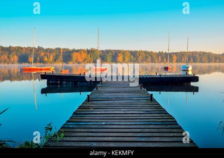 Bellissimo paesaggio autunnale. molo in legno e in barca sul lago. Foto Stock
