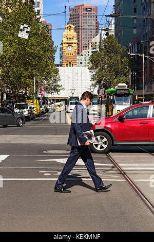 Il lavoratore cittadino utilizza lo smartphone durante l'attraversamento di Elizabeth Street a Melbourne Victoria Australia. Foto Stock