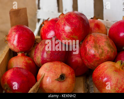 Ripe rosso melograno in una scatola di legno su tela marrone Foto Stock