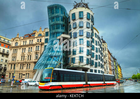 Mozzafiato paesaggio urbano di Praga, moderno rosso elettrico tram, con una fantastica casa Danzante (tancici dum) edificio in background su un giorno di pioggia, Praga, Foto Stock