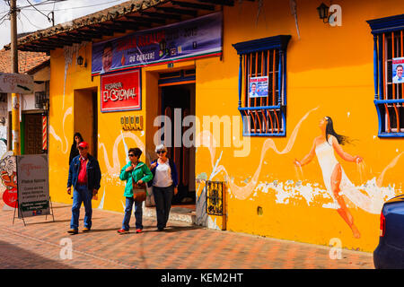 Colombia, Sud America - persone che lasciano il Restaurante El Colonial nella città di Nemocón, nel dipartimento di Cundinamarca. Luce del sole del pomeriggio. Foto Stock