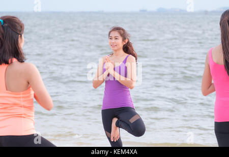 Asia femmina facendo yoga posa ad albero e namaste con calma relax emozione a beach,sport training di gruppo di classe,meditazione pongono,di benessere e salute lifestyl Foto Stock