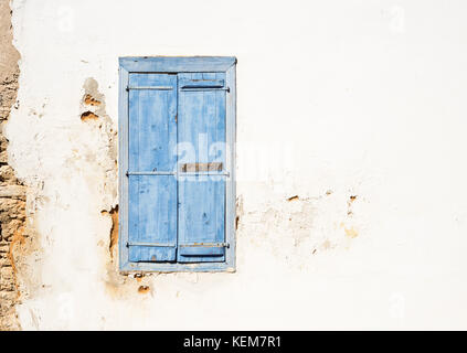 Vecchia finestra in stile mediterraneo. Blu su parete luminosa con persiane chiuse. Foto Stock