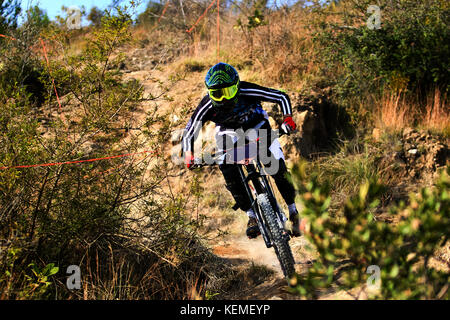 Downhill mountain biker sul costume nero facendo un giro veloce durante la guida in discesa Foto Stock