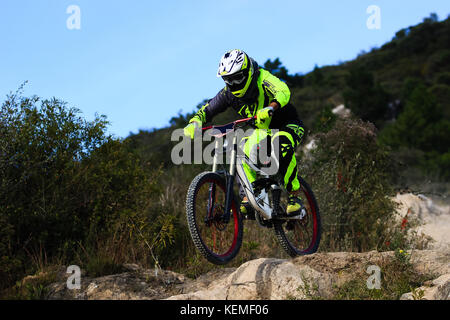 Downhill mountain biker su un costume giallo facendo un piccolo salto Foto Stock