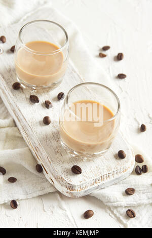 Irish cream di liquore al caffè e caffè in chicchi di colore bianco su sfondo di legno - festa in casa bevanda alcolica Foto Stock