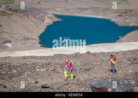 Due alpinisti con attrezzatura per raggiungere a piedi la montagna in giornata di sole Foto Stock