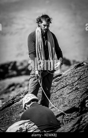 Bianco e nero colpo di scalatore due uomini con la fune in posizione eretta e seduta sulla montagna Foto Stock