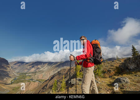 Bel giovane maschio escursionista seduta sul bordo di un canyon che guarda lontano Foto Stock