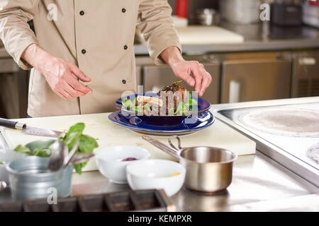 Lo chef maschio e gambo di agnello con verdure. chef di cucina professionale cotto gambo di agnello con ratatouille di verdure. delizioso piatto a livello europeo resta Foto Stock