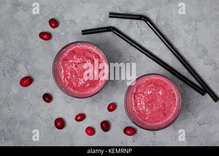 Cranberry frullati in bicchieri su un cemento grigio Sfondo. vista da sopra Foto Stock